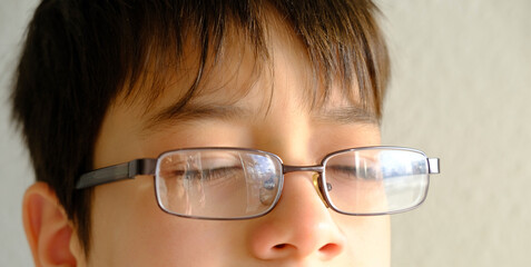 closeup child's face, eyes of boy 10-12 years old in glasses, concept of vision examination, eyestrain, diagnosis, treatment of ophthalmic diseases, eyelids, emotional development of children