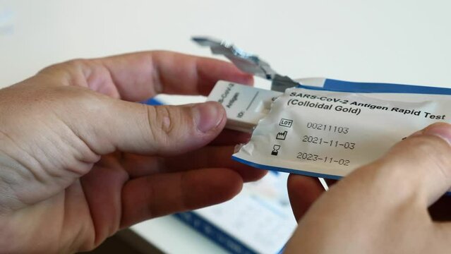 Man hands open sealed sterile package with fast coronavirus antigen test for self diagnosis at home. Rapid atk covid-19 test kit unpacking process, preparing to perform to check infection status.
