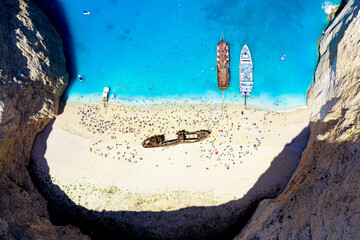Crowd of tourists sunbathing on the idyllic Shipwreck Beach (Navagio Beach), aerial view, Zakynthos island, Greek Islands