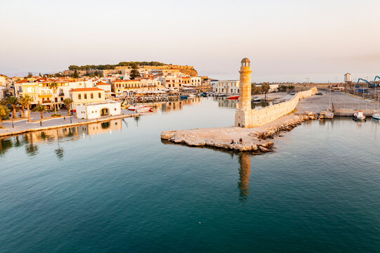 Aerial view of the calm sea at dawn surrounding the old Venetian port and lighthouse, Rethymno, Crete island, Greek Islands