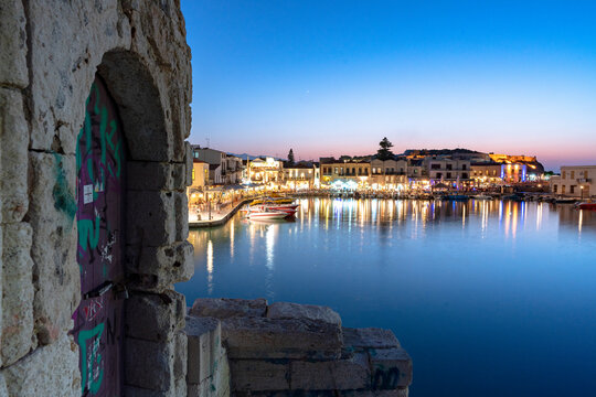 Lights of old Venetian port reflected in the sea at dusk, Rethymno, Crete island, Greek Islands