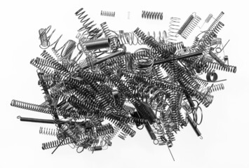 Pile of metal flexible coiled springs from spiral wire of various sizes on white background. Abstract jumble of many steel elastic compression, tension and torsion mechanical devices for store energy.