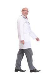 Mature doctor with stethoscope walking on white background