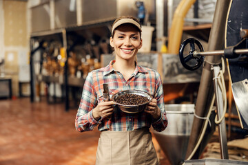 A coffee factory worker showing roasted coffee beans at the camera.