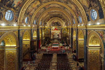 Panoramic interior view of Roman Catholic St. John Co-Cathedral with golden Maltese cross symbols on arches, Valletta, Malta