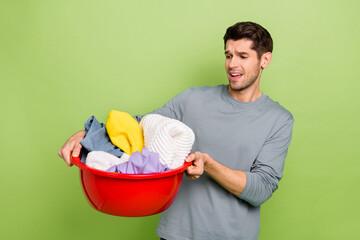 Photo of millennial sad brunet guy do laundry wear shirt isolated on green color background