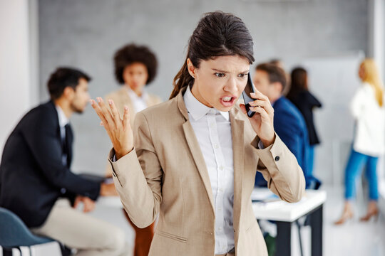 An angry businesswoman yelling on the phone at the office.