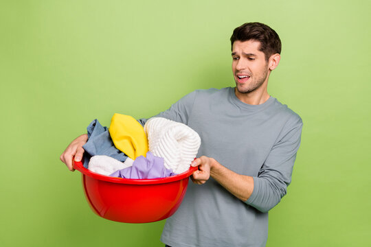 Photo of millennial sad brunet guy do laundry wear shirt isolated on green color background