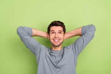 Photo of cute millennial brunet guy look up wear grey pullover isolated on green color background