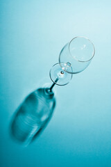 Empty wine glass with a creative shadow on blue background.