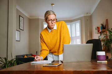 Caucasian female working from home writing on document 