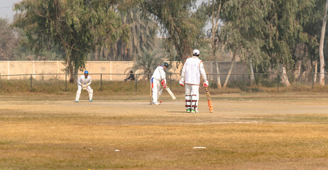 young boys playing cricket in the local city playground 