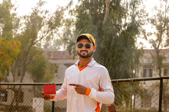 Young Cricketer Holding Empty Box On Hand On Match Ground