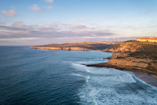 Ericeira drone aerial view on the coast of Portugal with surfers on the sea at sunset, Lisbon area, Portugal
