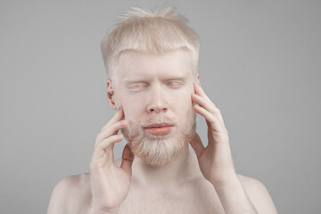 Young albino man posing over grey backgound, guy with unusual appearance, white hair, beard,...