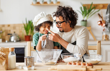 Cheerful black father and son cooking and having fun