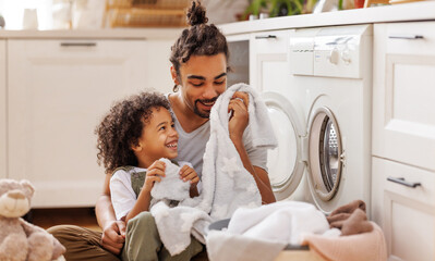 Son helping dad to load washing machine