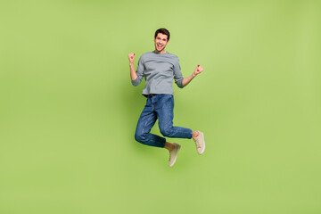 Full size photo of overjoyed crazy delighted man jumping in excitement win money lottery isolated on green color background