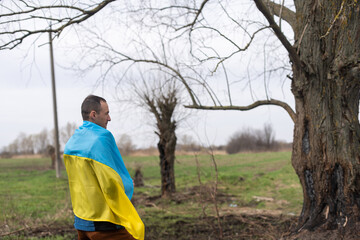 successful silhouette man winner waving Ukrainian flag near a burnt tree