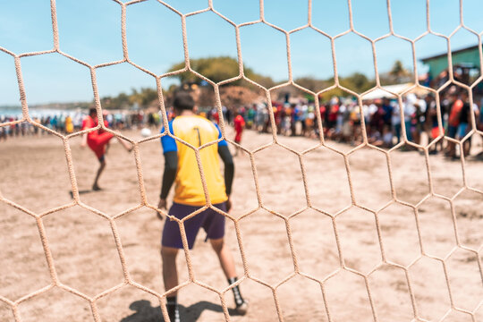 Selective focus photo of an unrecognizable goalkeeper protecting the goal during a soccer game on a beach in Masachapa, Nicaragua. Concept of popular sports in Latin America.