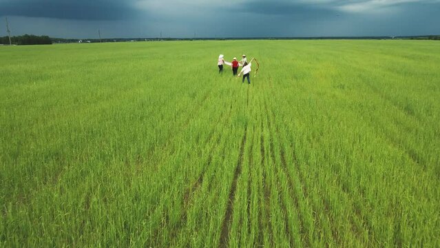A happy family runs amicably across the green field, throwing their hats. Friendly family vacation, nature hike from a bird's eye view. People spend their time in the open air carefree. Copy space. 4K