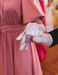 Couples dance on the historical costumed ball in historical dresses, classical ballroom dancers dancing, waltz, quadrille and polonaise in palace interiors on a wooden floor, opera gloves close-up