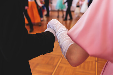 Couples dance on the historical costumed ball in historical dresses, classical ballroom dancers dancing, waltz, quadrille and polonaise in palace interiors on a wooden floor, opera gloves close-up