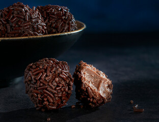 truffles on a dark wooden table with a black bowl next to it and a dark blue background horizontal shot dark food photography