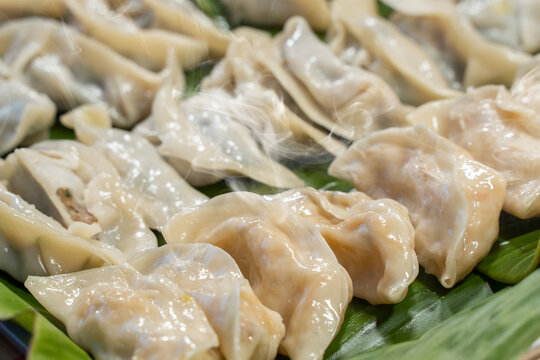 Close up fresh boiled dumplings with hot steams . Chinese food on banana leaves background.