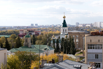 Fototapeta premium View of roofs of buildings and dome of church with cross in city center