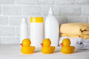 Baby bath accessories, towel, yellow rubber duck and shampoo bottles. The concept of child care.
