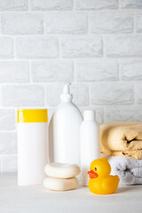 Baby bath accessories, towel, yellow rubber duck and shampoo bottles. The concept of child care.