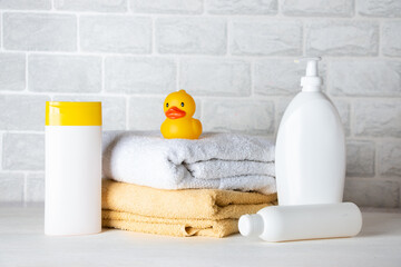 Baby bath accessories, towel, yellow rubber duck and shampoo bottles. The concept of child care.