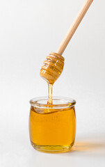 Honey pot and dripping honey with wooden spoon