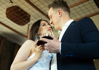Young newlywed couple drinking wine and smiling at their happiness, romance and tenderness