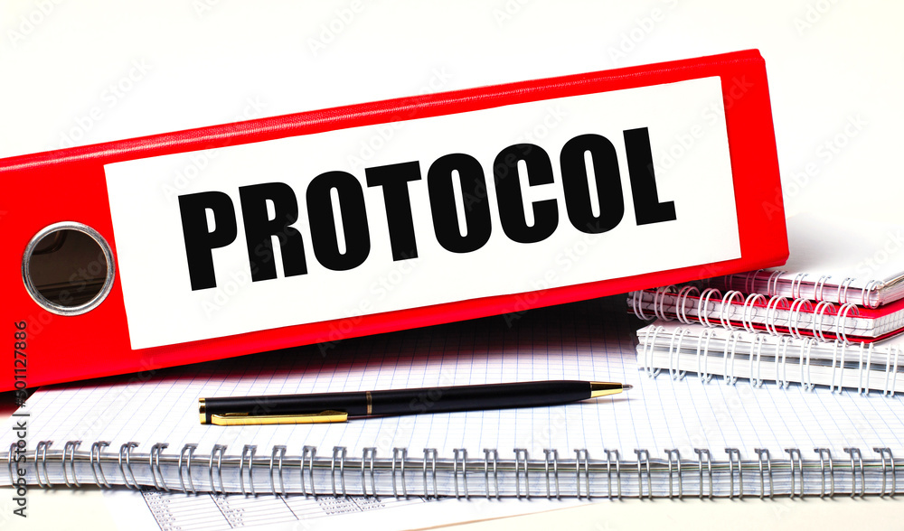 Poster on the desktop are notebooks, a pen and a red folder for papers with the text protocol. business con