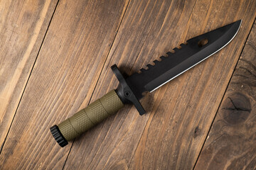A modern military knife and a plastic sheath for it. Edged weapons lie on a military olive-colored backpack.