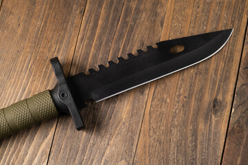 A modern military knife and a plastic sheath for it. Edged weapons lie on a military olive-colored...