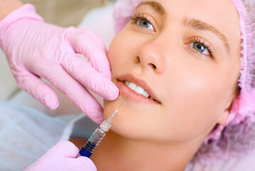 Image of a young beautiful woman dressed as a patient, lying on a couch in a cosmetology clinic.