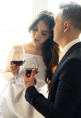 Young newlywed couple drinking wine and smiling at their happiness, romance and tenderness