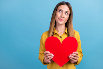 Photo of coquette mature brown hairdo lady hold heart look up wear yellow shirt isolated on blue color background