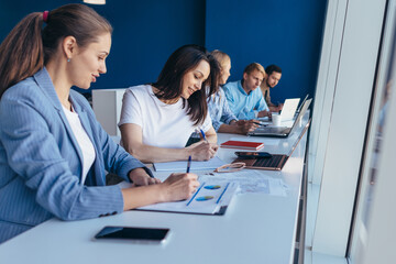 Students sit at a table and perform academic tasks