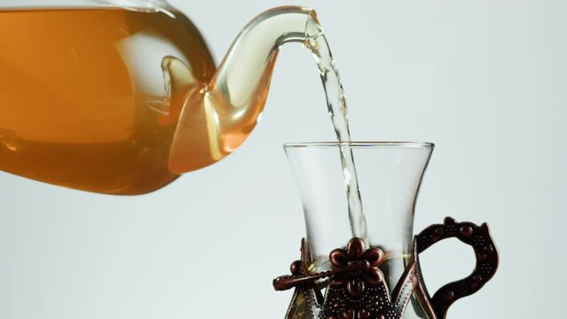 Pouring citrus black tea in armudu glass on white background. Freshly brewed green tea ceremony process, healthy morning, detox drink.