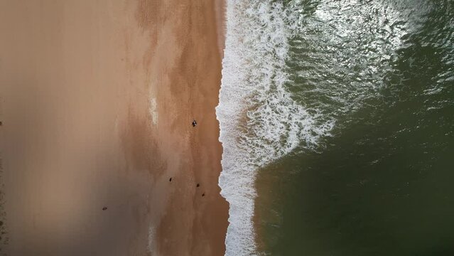 Aerial top down view of beach in Falesia, Vilamoura, Portugal with unidentifiable beachgoers walking on the sand