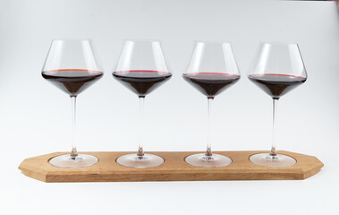 Four glasses with red wine on a wooden stand.
