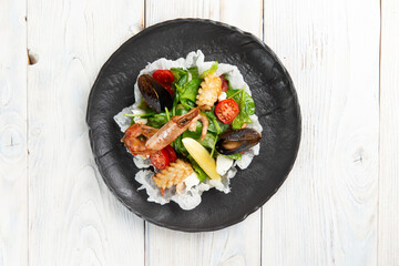 Salad with seafood in a bowl. On a light background.