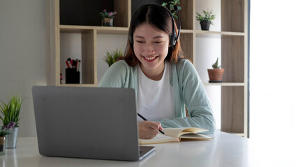 Happy young woman in headphones speaking looking at laptop making notes, girl student talking by video conference call, female teacher trainer tutoring by webcam, online training, e-coaching concept