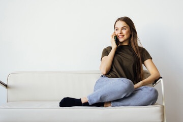 Fototapeta premium Young woman talk phone listen use laptop stay home sit sofa indoors