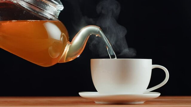 Pouring citrus black tea on black background. Freshly brewed green tea ceremony process, healthy morning, detox drink.