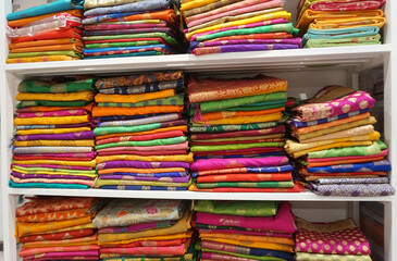 Colorful sarees or saris are arrange on racks and display in a retail shop, for use as indian textiles background.